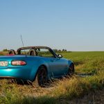 A blue convertible in the scenic countryside of Słomniki, Poland on a sunny day.